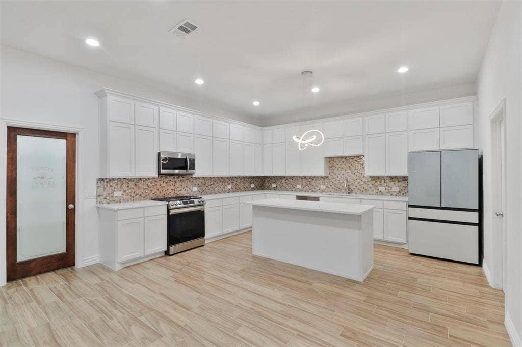 4112 Balch Drive, Dallas, TX 75216 Modern kitchen featuring white cabinetry, stainless steel appliances, and a large center island with white countertop