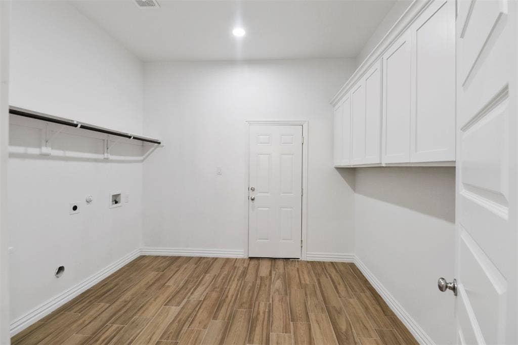 4112 Balch Drive, Dallas, TX 75216 Laundry room featuring wood-finish flooring, white cabinetry, integrated lighting, and a built-in hanging rod