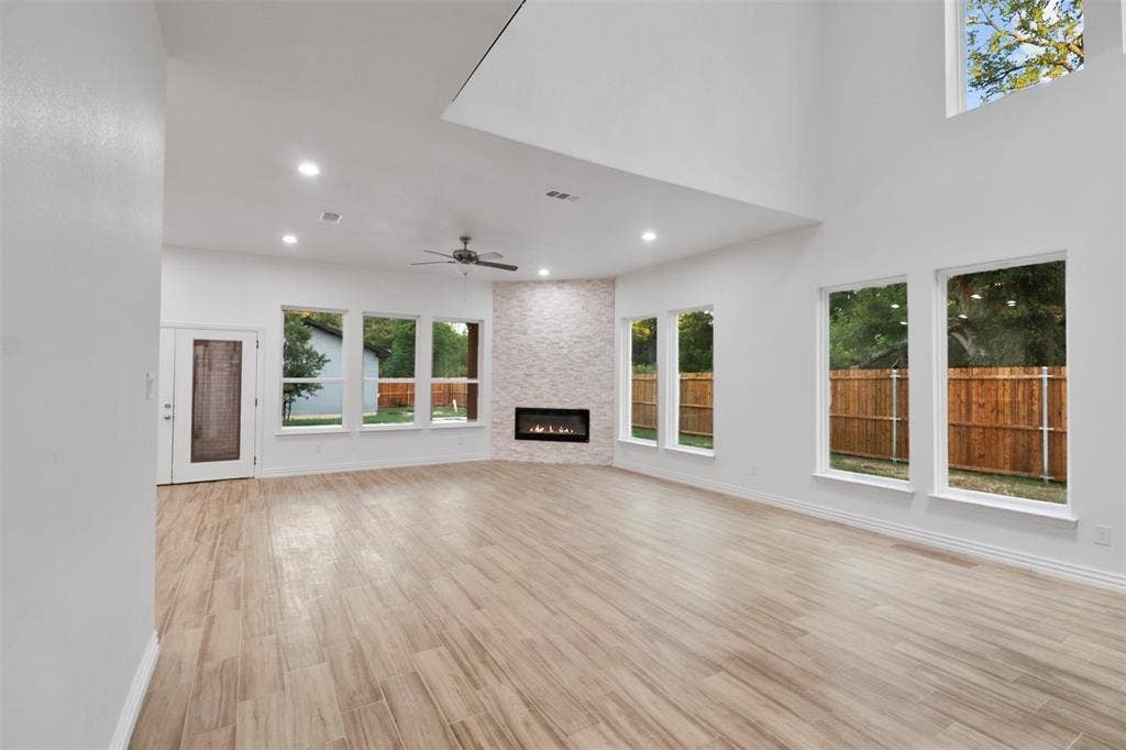 4112 Balch Drive, Dallas, TX 75216 Spacious open-concept living area featuring soaring ceilings with skylight, wood-finish flooring throughout, and multiple sets of glass French doors opening to outdoor space