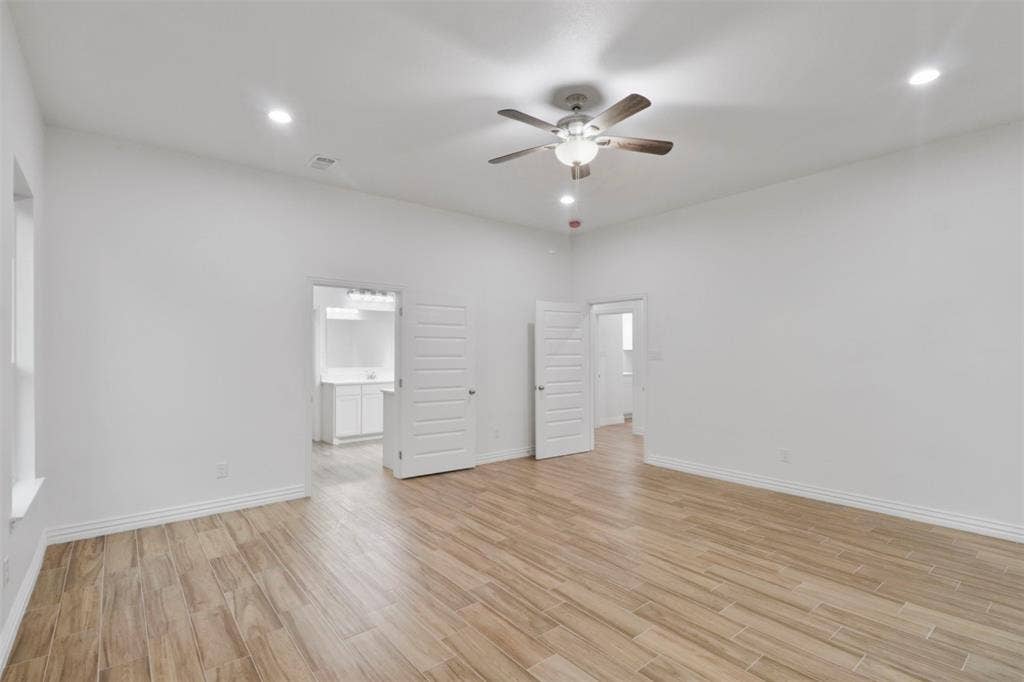 4112 Balch Drive, Dallas, TX 75216 Spacious bedroom showcasing pristine white walls, wood-finish flooring throughout, and recessed ceiling lighting