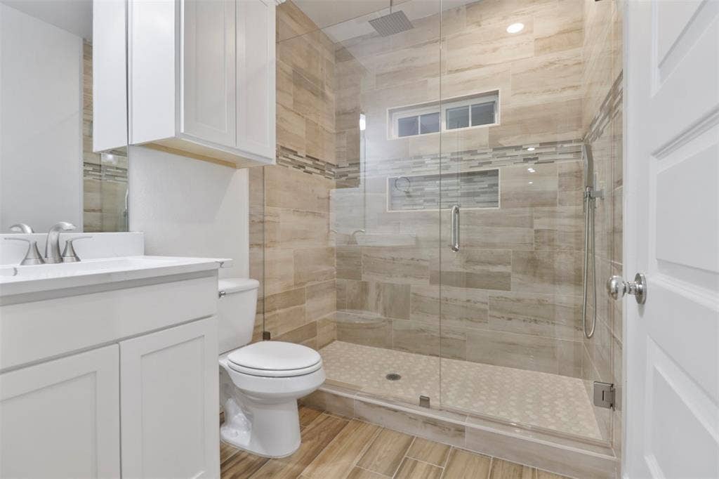 4112 Balch Drive, Dallas, TX 75216 Spa-inspired primary bathroom featuring a frameless glass-enclosed shower with linear tile surround, dual showerheads, and a rainfall fixture