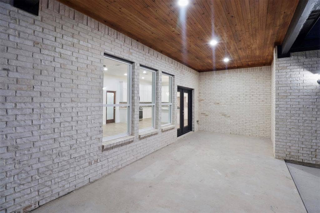 4112 Balch Drive, Dallas, TX 75216 Spacious open floor plan featuring white brick walls, polished concrete flooring, and a wood-finish coffered ceiling with recessed lighting