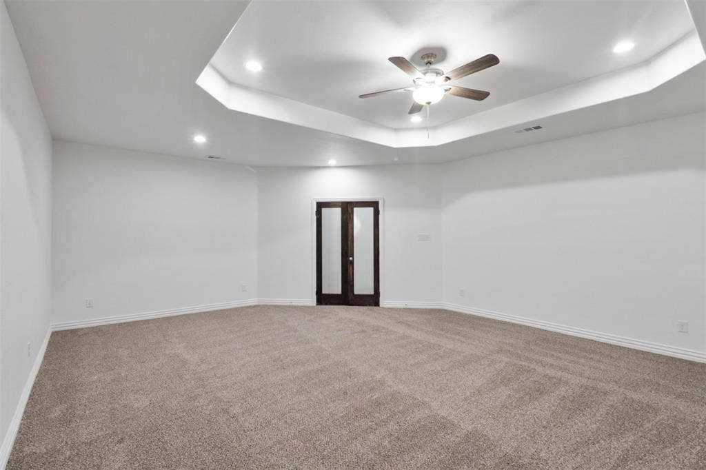 4112 Balch Drive, Dallas, TX 75216 Spacious room featuring a tray ceiling with recessed lighting, a ceiling fan, plush carpet flooring, and dark wood-finish double doors with glass panels
