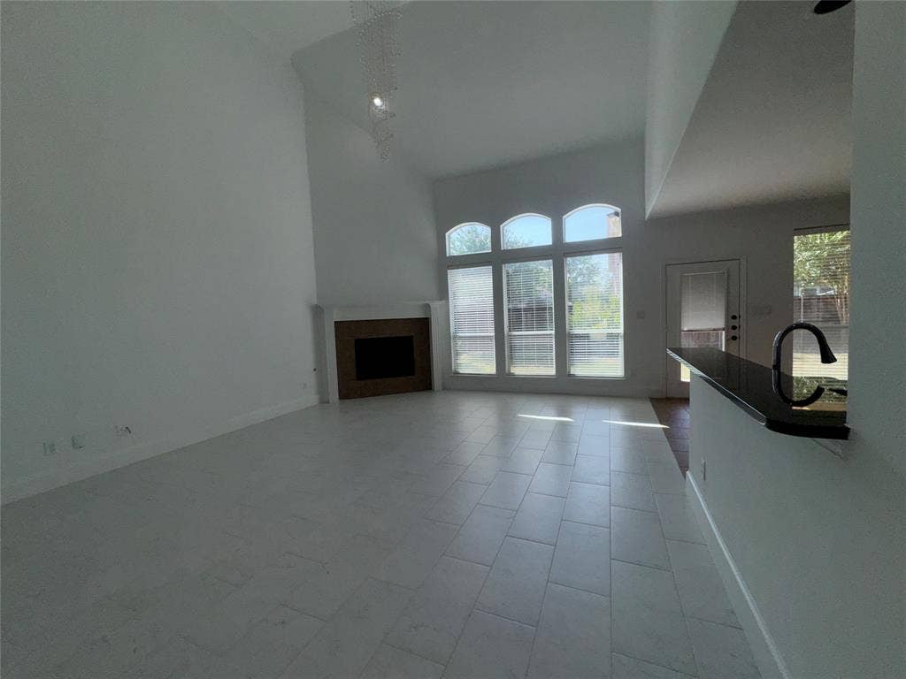 1913 Lawnview Drive, McKinney, TX 75072 Bright, open living space featuring soaring vaulted ceilings, large multi-pane glass doors flooding the room with natural light, and neutral tile flooring