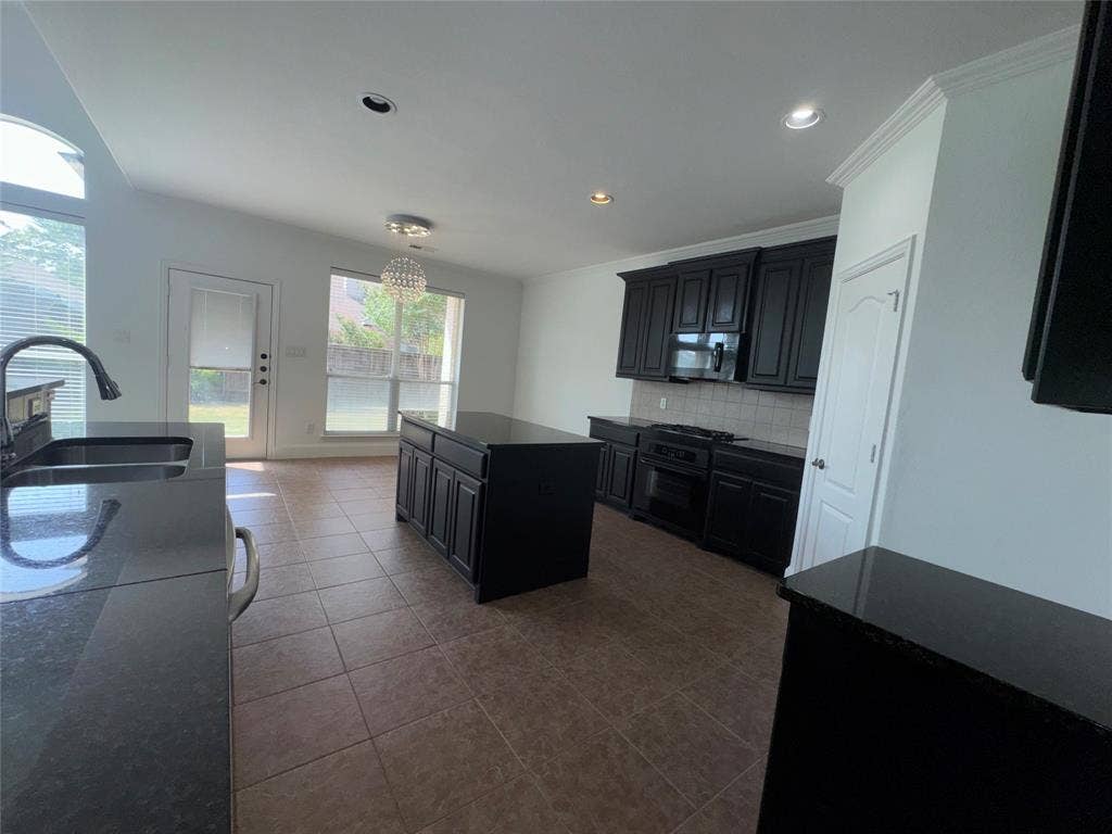 1913 Lawnview Drive, McKinney, TX 75072 Spacious kitchen featuring dark cabinetry, stainless steel appliances, and an island with seating