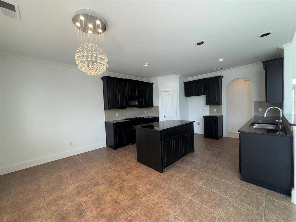 1913 Lawnview Drive, McKinney, TX 75072 Spacious kitchen featuring black cabinetry, a large center island with seating, stainless steel appliances including a professional-style range, and cork-finish flooring throughout