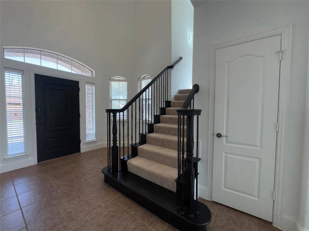1913 Lawnview Drive, McKinney, TX 75072 Two-story foyer with tile flooring and a grand staircase featuring dark wood newel posts and wrought iron balusters