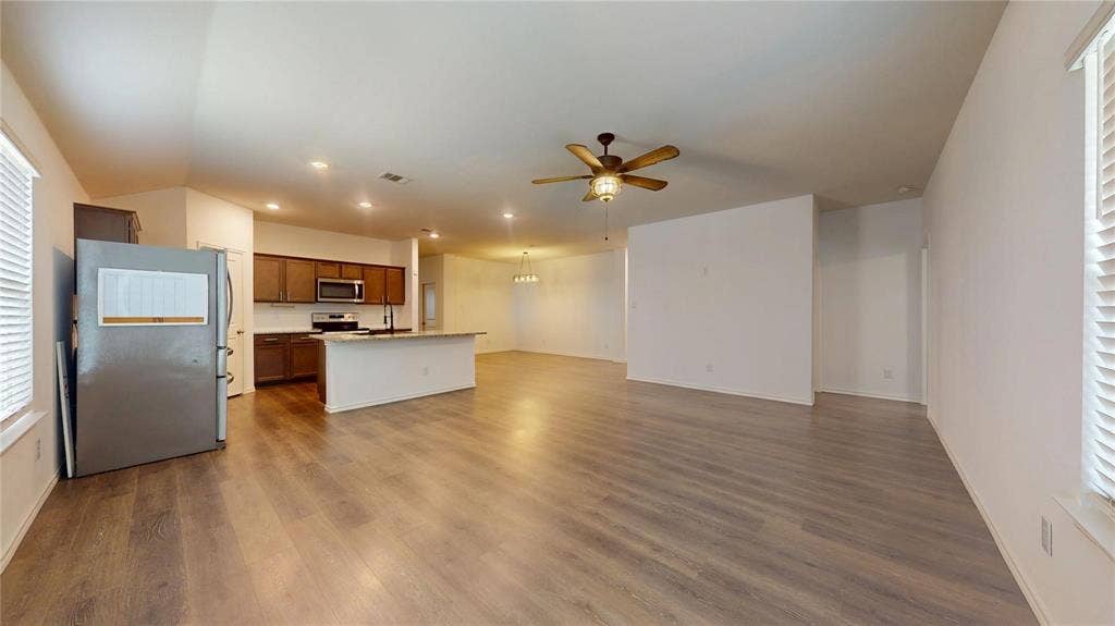 717 Cottonwood Way, Royse City, TX 75189 Spacious open-concept living area featuring wood-finish flooring, a kitchen island with seating, dark wood cabinetry, and a ceiling fan