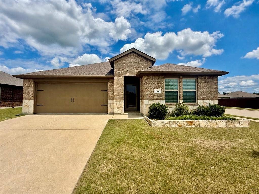 717 Cottonwood Way, Royse City, TX 75189 Brick and stone exterior featuring an attached two-car garage with decorative hardware