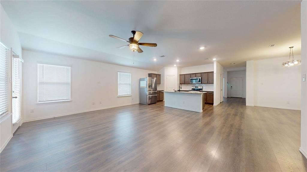 717 Cottonwood Way, Royse City, TX 75189 Expansive open-concept living space featuring wood-finish flooring throughout, a modern ceiling fan, and recessed lighting