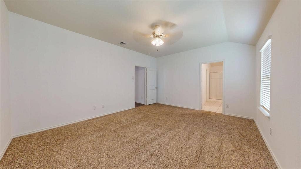 717 Cottonwood Way, Royse City, TX 75189 Spacious carpeted room featuring a vaulted ceiling with a flush-mount ceiling fan, white painted walls, and a window with blinds
