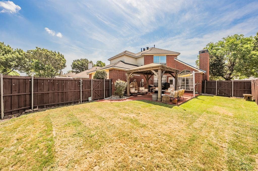 812 Chaparral Drive, Grand Prairie, TX 75052 Expansive backyard featuring a large grass area, a wooden privacy fence, and a covered patio with a gazebo structure
