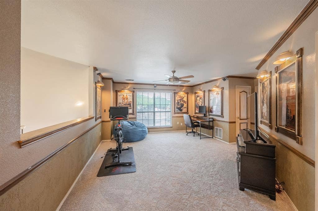 812 Chaparral Drive, Grand Prairie, TX 75052 Carpeted secondary living space featuring a ceiling fan, window with exterior views, crown molding, and wall sconces