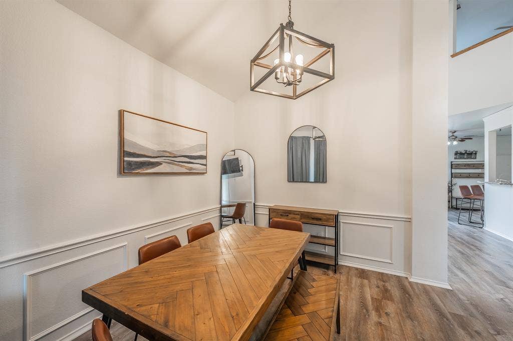 812 Chaparral Drive, Grand Prairie, TX 75052 Dining area featuring vaulted ceilings, wood-finish flooring, and wainscoting with decorative trim