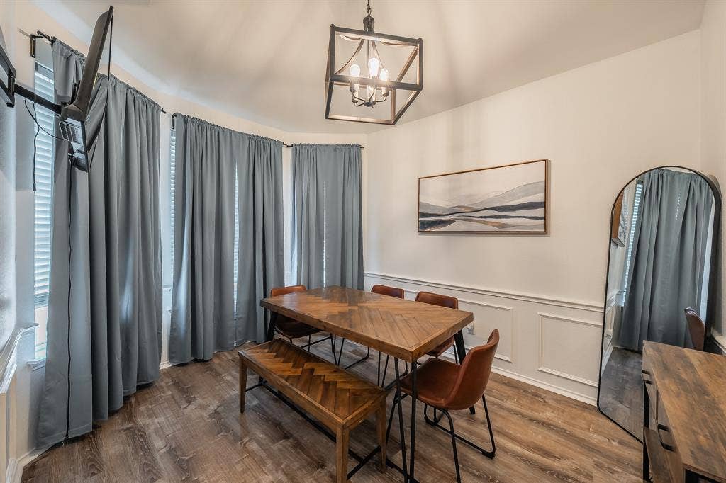 812 Chaparral Drive, Grand Prairie, TX 75052 Dining area featuring bay windows with blinds, wood-finish flooring, and wainscoting
