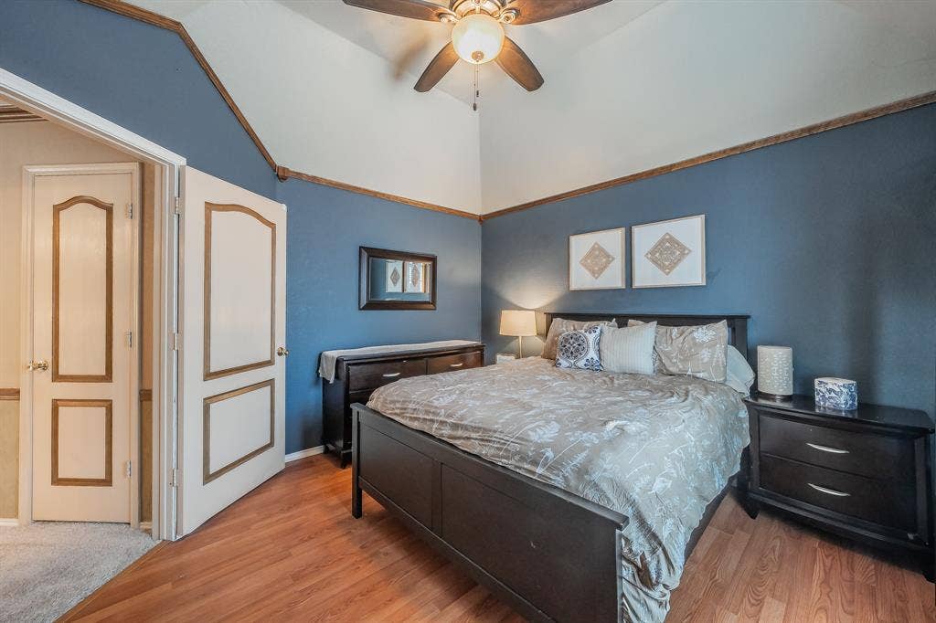 812 Chaparral Drive, Grand Prairie, TX 75052 Spacious room featuring vaulted ceilings, a ceiling fan with integrated lighting, wood-finish flooring, and a paneled door with decorative trim