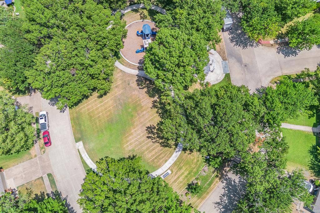 812 Chaparral Drive, Grand Prairie, TX 75052 Circular green space featuring a playground with blue equipment, surrounded by mature trees