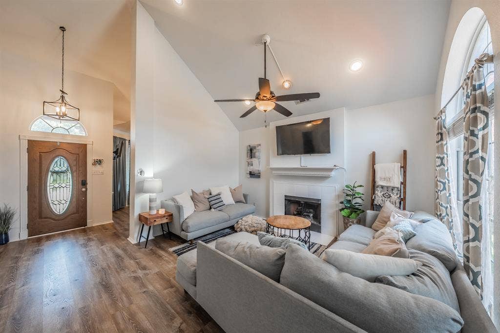 812 Chaparral Drive, Grand Prairie, TX 75052 Vaulted ceilings accent this living area featuring a fireplace with a white mantel, ceiling fan, recessed lighting, and wood-finish flooring