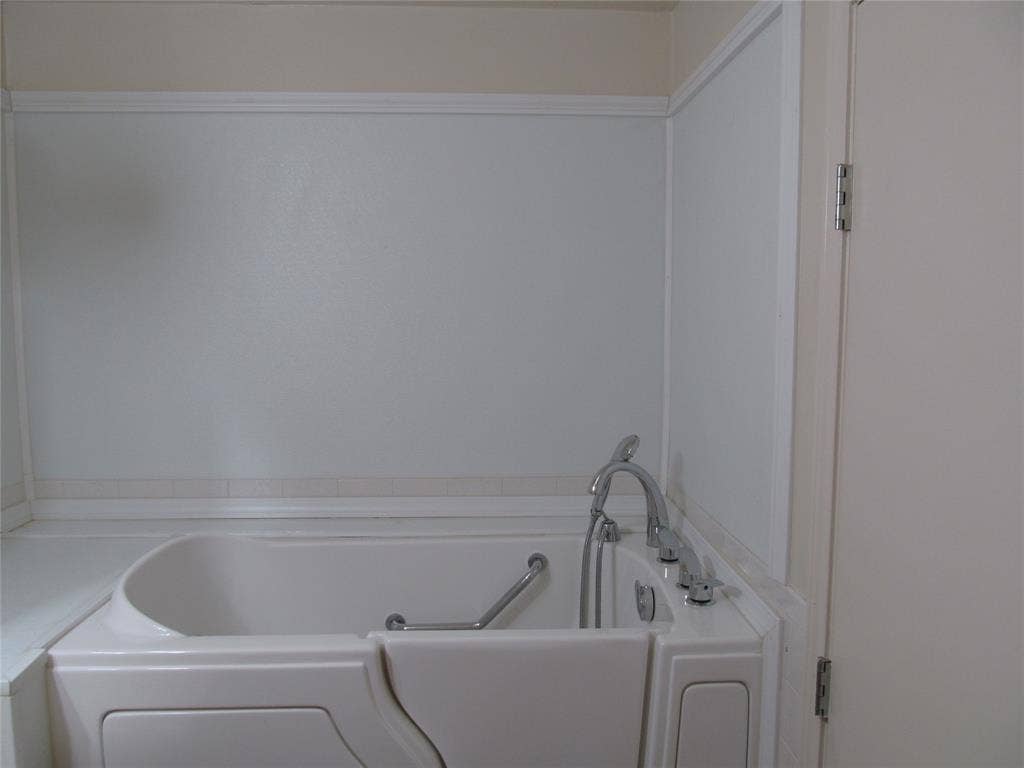 740 Emberwood Drive, Dallas, TX 75232 White walk-in bathtub with integrated grab bar and chrome fixtures