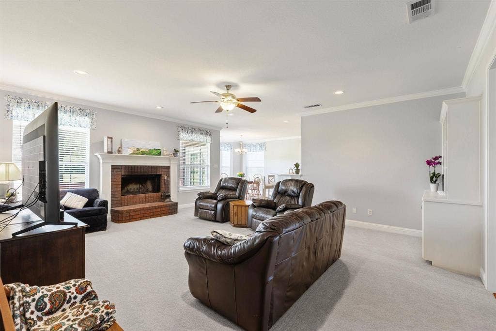 Living area featuring a brick fireplace with a white mantle, ceiling fan, recessed lighting, and light-toned carpeting