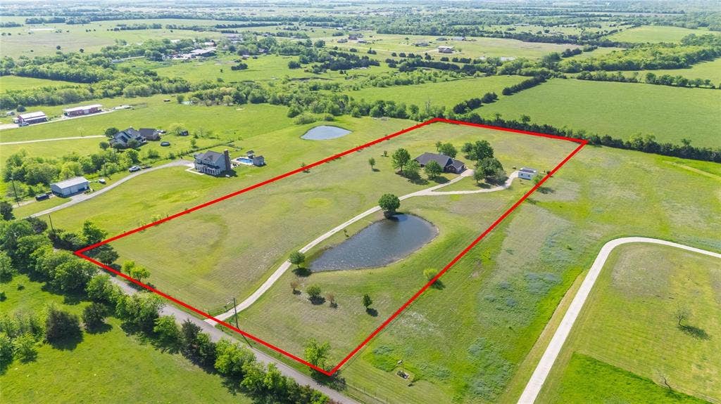 Expansive rural property featuring a main residence, additional structure, two private ponds, and extensive open green spaces
