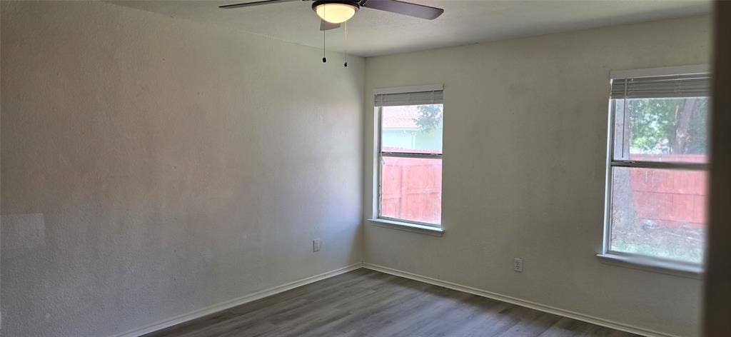 4809 Orchard Ridge Drive, Garland, TX 75043 Room featuring two windows with blinds, a ceiling fan with integrated lighting, and wood-finish flooring