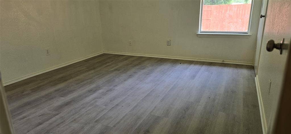 4809 Orchard Ridge Drive, Garland, TX 75043 Interior room featuring wood-finish flooring, light-toned walls, a window with a white frame, and white baseboards