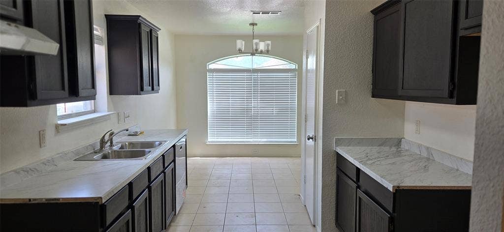 4809 Orchard Ridge Drive, Garland, TX 75043 Kitchen featuring dark wood-finish cabinetry, light-toned countertops, a double basin stainless steel sink, and a built-in dishwasher