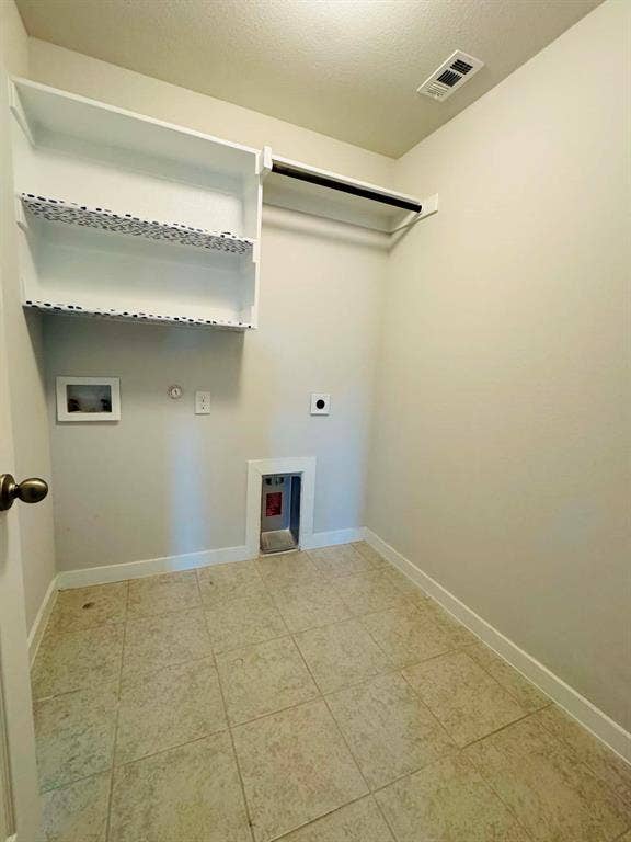 Fort Worth, TX 76123 Dedicated utility space featuring tile flooring, white baseboards, wall-mounted shelving, and a hanging rod