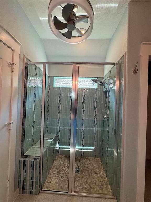Fort Worth, TX 76123 Glass-enclosed shower with pebble-finish flooring, tiled walls, a built-in bench, and a transom window