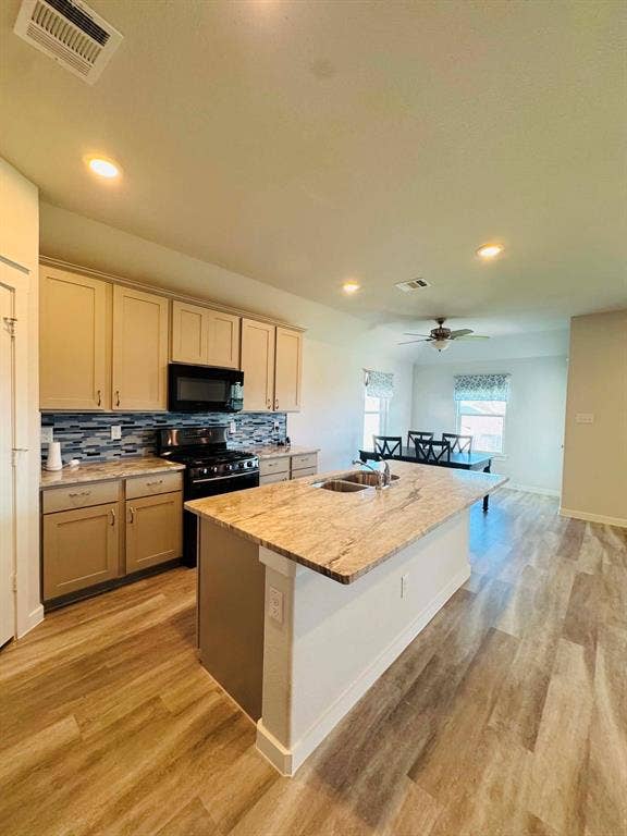 Fort Worth, TX 76123 Kitchen featuring a large central island with a built-in sink, stone countertop, and integrated seating