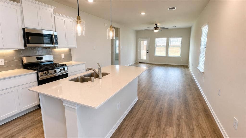 1317 crookpost Drive, Princeton, TX 75407 Kitchen island with dual basin sink, integrated stainless steel appliances, and white shaker cabinetry