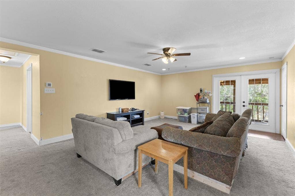 325 Bolton Road, Granbury, TX 76049 Carpeted living area featuring recessed lighting, a ceiling fan, crown molding, and double glass-paneled doors leading to an outdoor space