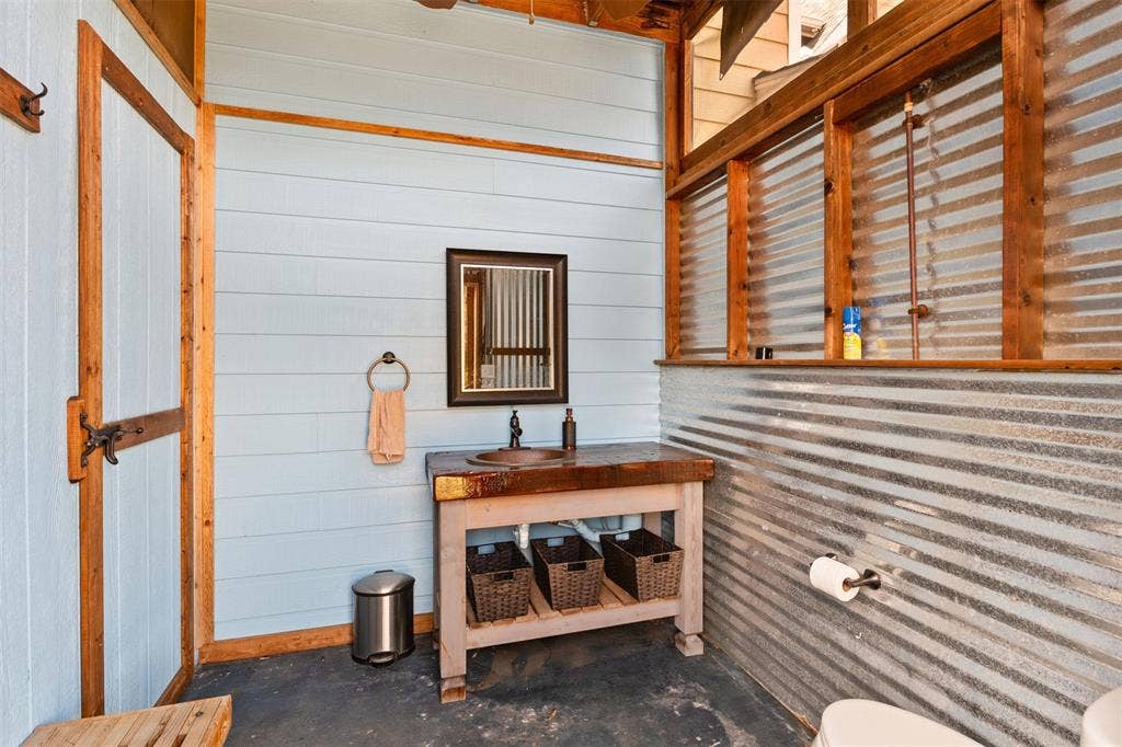 325 Bolton Road, Granbury, TX 76049 Open-air bathroom featuring a wood-finish vanity with an integrated sink, corrugated metal wall accents, and light blue wall paneling