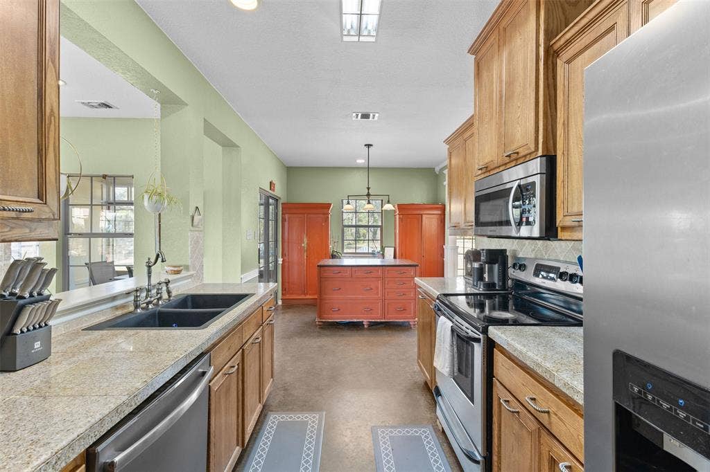 325 Bolton Road, Granbury, TX 76049 Galley kitchen with light-toned cabinetry, granite-style countertops, stainless steel appliances, and a double basin sink