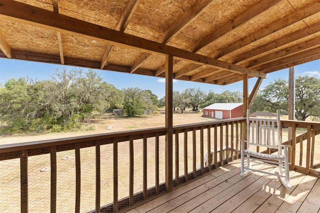 325 Bolton Road, Granbury, TX 76049 Covered wood-plank deck with wood railing, featuring an exposed wood-beam ceiling structure