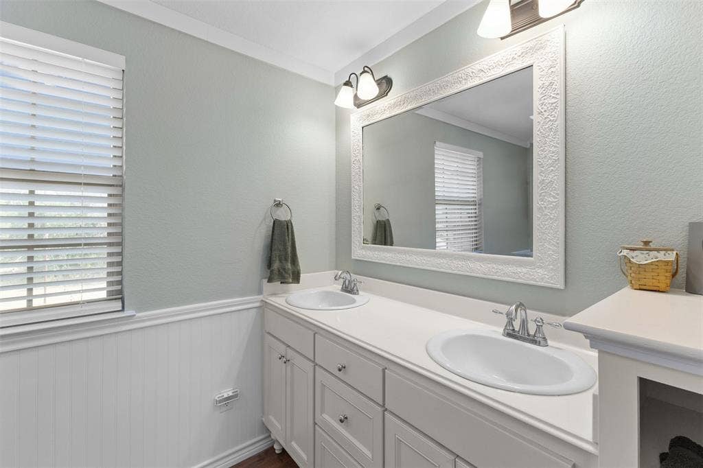 325 Bolton Road, Granbury, TX 76049 Double vanity with integrated sinks, white cabinetry, and a large decorative framed mirror