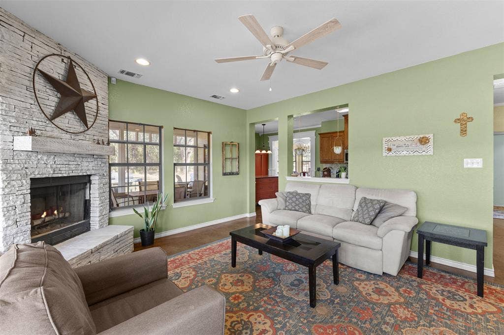 325 Bolton Road, Granbury, TX 76049 Living area featuring a floor-to-ceiling stacked stone fireplace, a wood mantel, and large multi-pane windows