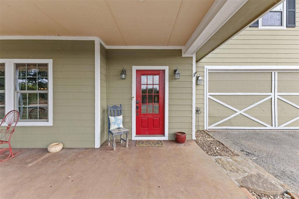 325 Bolton Road, Granbury, TX 76049 Covered entry with a red door, exterior wall sconces, and light-colored siding