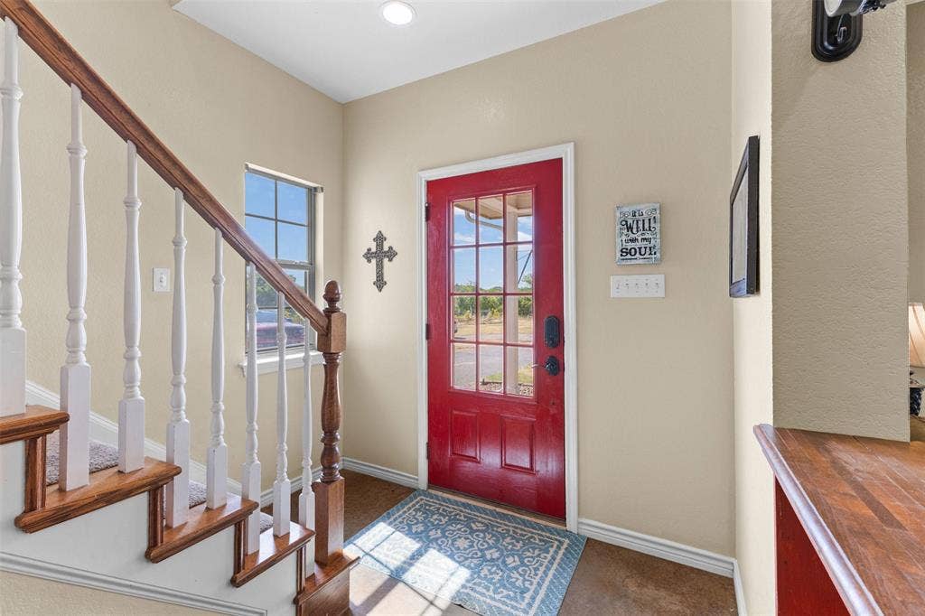 325 Bolton Road, Granbury, TX 76049 Warm red entry door with glass panels, wood-finish flooring, and a staircase featuring wood treads and white risers