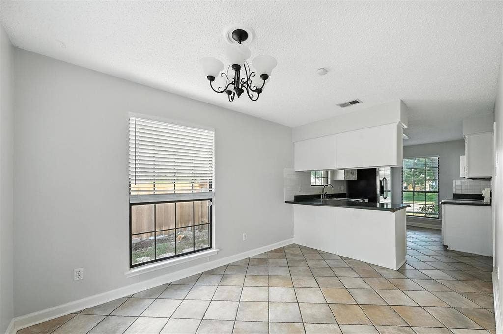 Charming brick ranch home featuring a manicured front lawn, mature shade trees, and a welcoming center entry with black-trimmed windows and doors