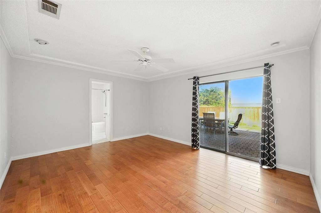 Spacious living area showcasing warm wood-finish flooring, white walls, and recessed ceiling lighting