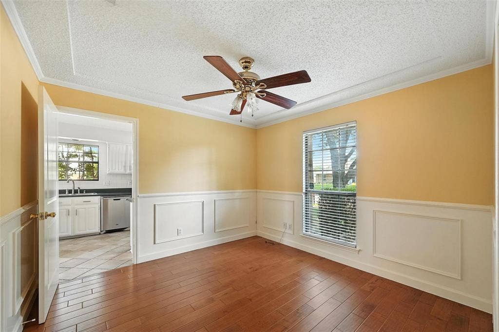 Bright and airy dining room showcasing warm yellow walls, classic wainscoting, and refinished hardwood flooring