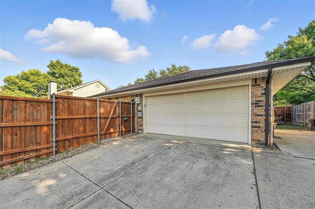Attached two-car garage with a paneled door, brick veneer siding, and a gabled roofline