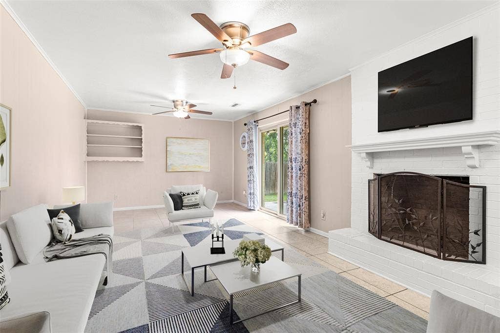6930 Trailcrest Drive, Dallas, TX 75232 Virtually Staged Spacious living area featuring a brick fireplace with a decorative mantel, ceiling fans, built-in shelving, and sliding glass doors leading to the exterior