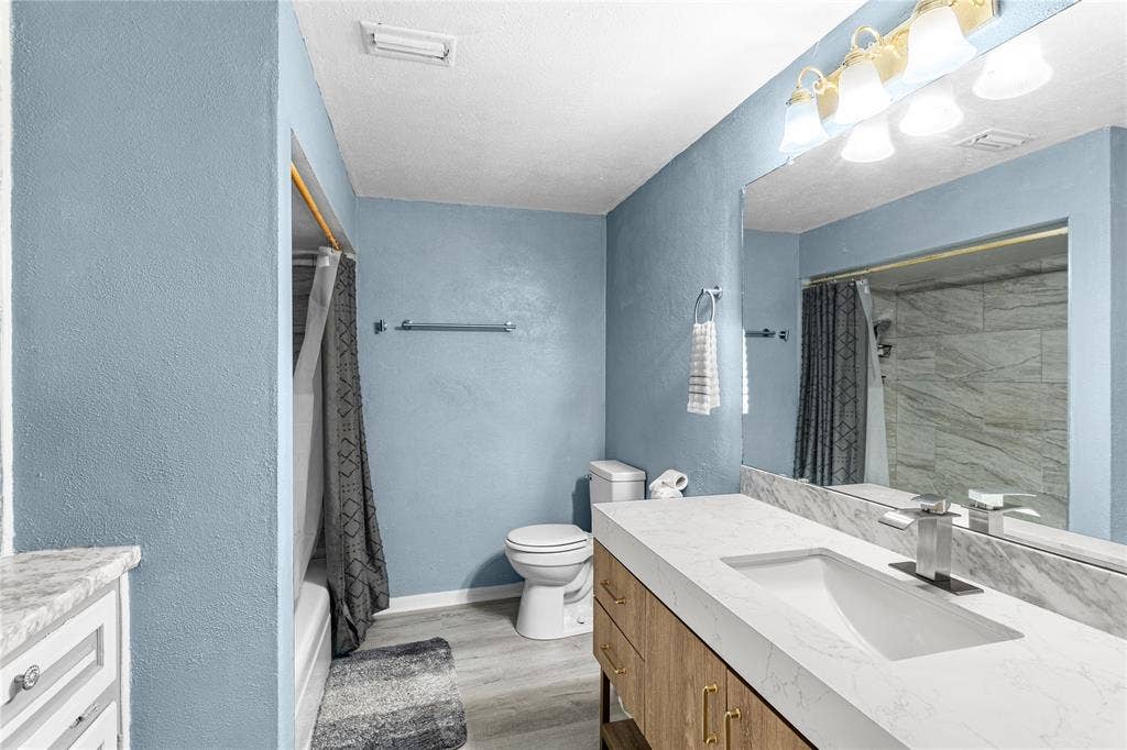 6930 Trailcrest Drive, Dallas, TX 75232 Bathroom featuring a single vanity with an integrated sink, a large mirror, and a shower-tub combination