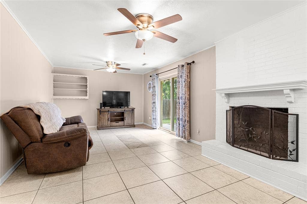 6930 Trailcrest Drive, Dallas, TX 75232 Living room with light-toned square tile flooring, a white-painted brick fireplace with a decorative screen, and a white mantelpiece