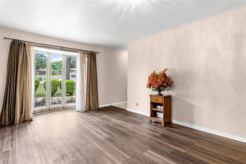 6930 Trailcrest Drive, Dallas, TX 75232 Bright living area featuring a bay window, wood-finish flooring, and neutral wall tones