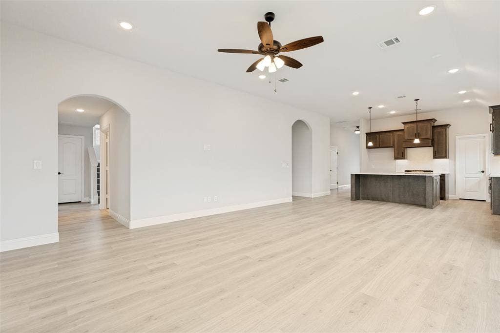 5405 Pooley Lane, McKinney, TX 75071 Spacious open-concept living area featuring light wood-finish flooring, recessed lighting, and an arched entryway