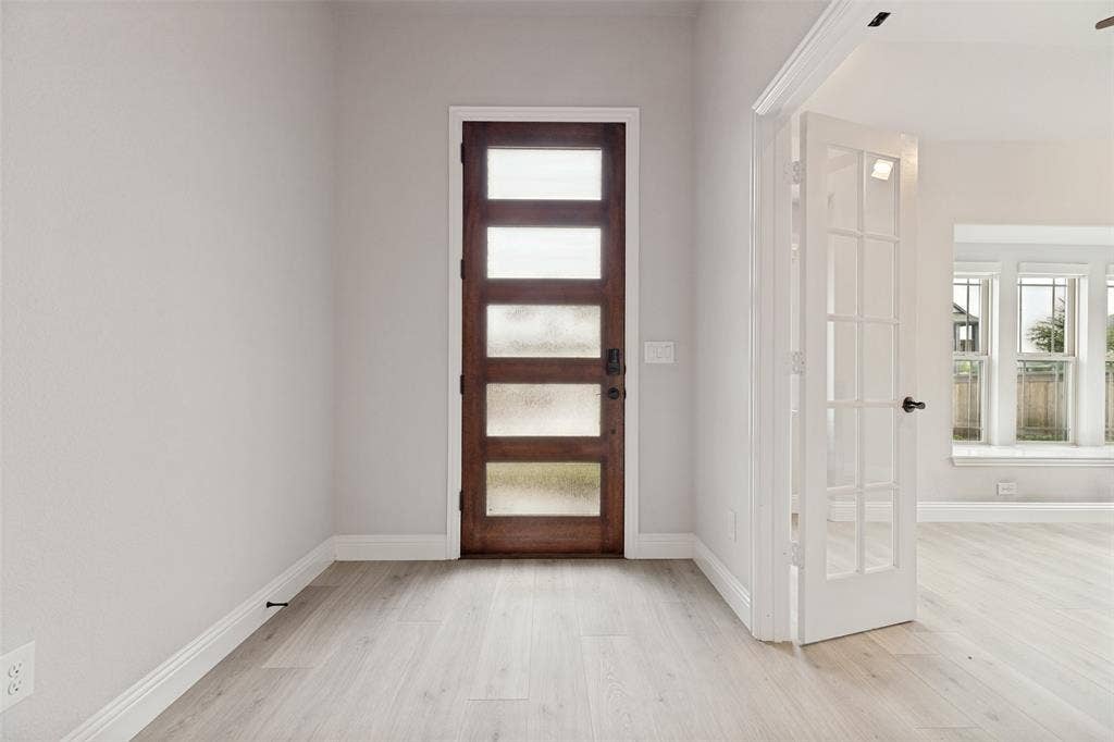 5405 Pooley Lane, McKinney, TX 75071 Entryway featuring a rich wood-finish front door with privacy glass panels, light wood-finish flooring, and crisp white baseboards